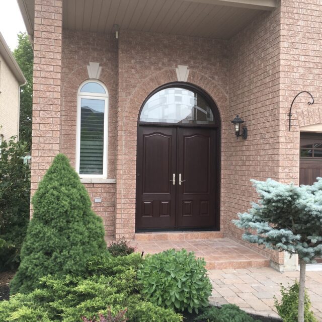 Double entry door with arched transom installed on a brick home exterior