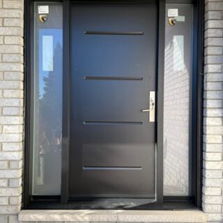 Modern black fiberglass entry door with sidelights installed on a residential home